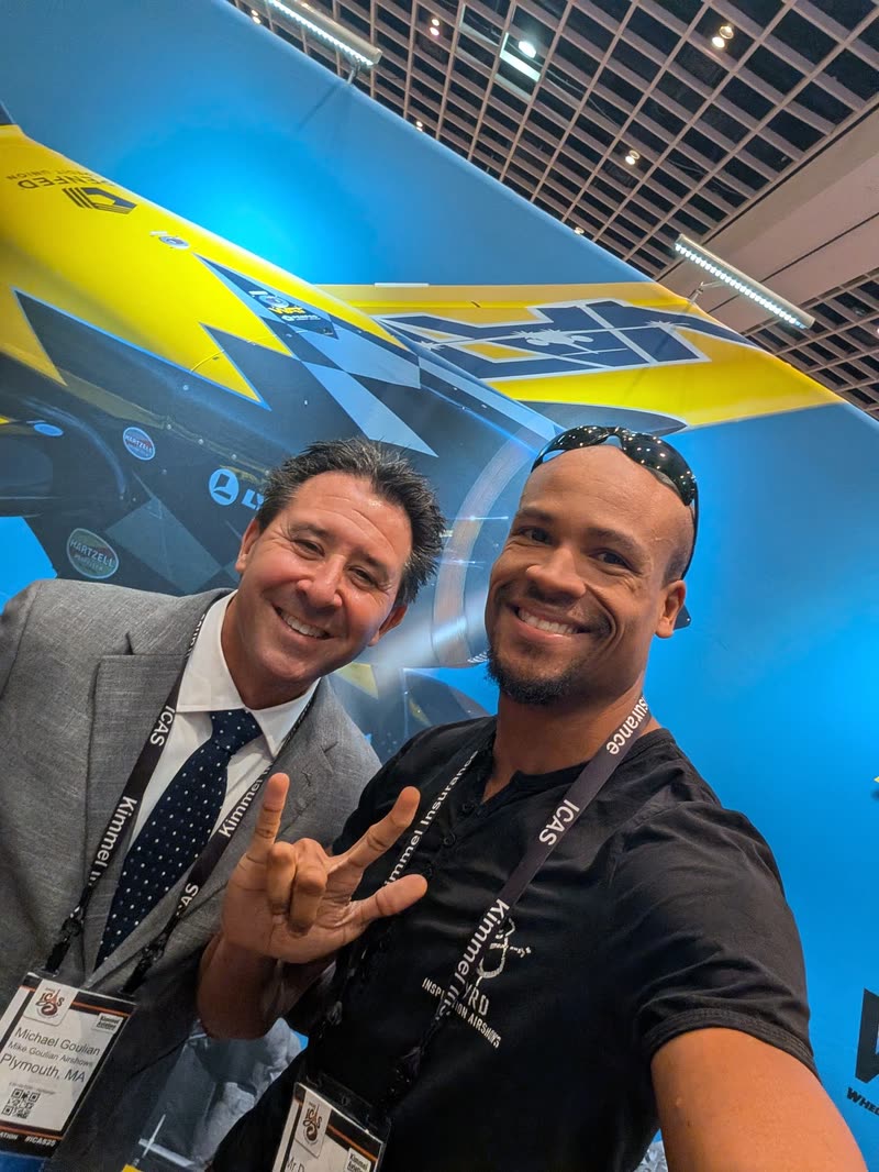 Doug Byrd smiling in a Byrd Inspiration Airshows tee, in a selfie with Michael Goulian at the ICAS convention.