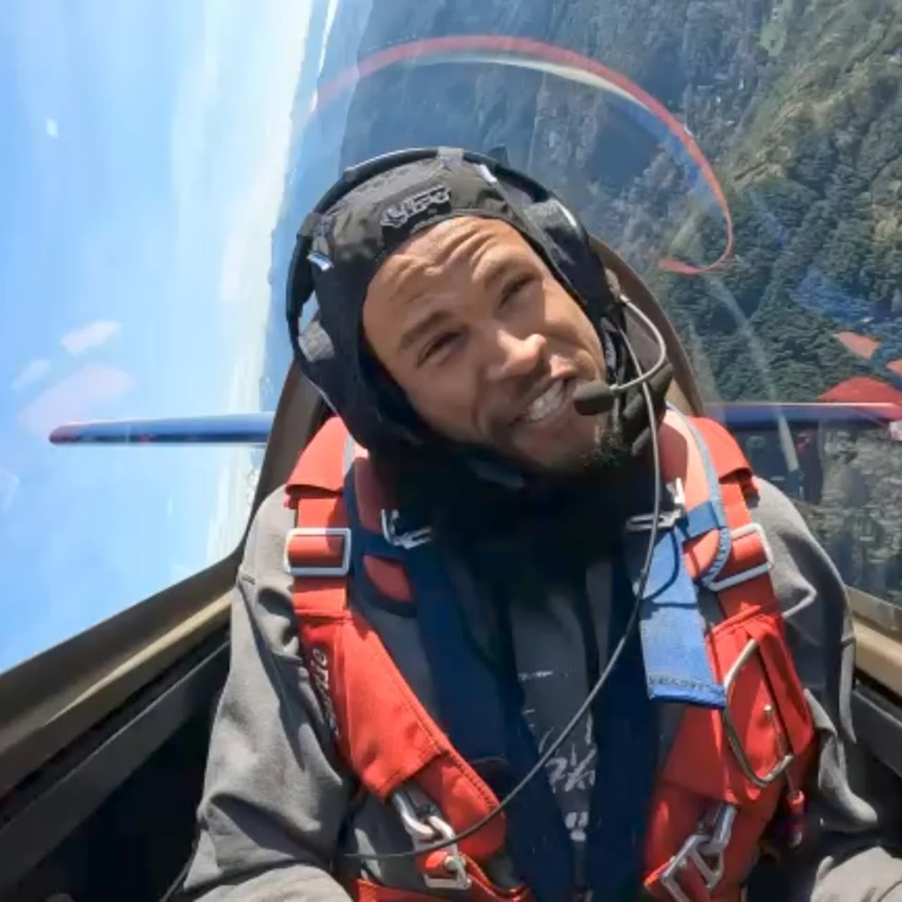 Doug Byrd grinning in the cockpit of an Extra 300L, helmet and harness on.