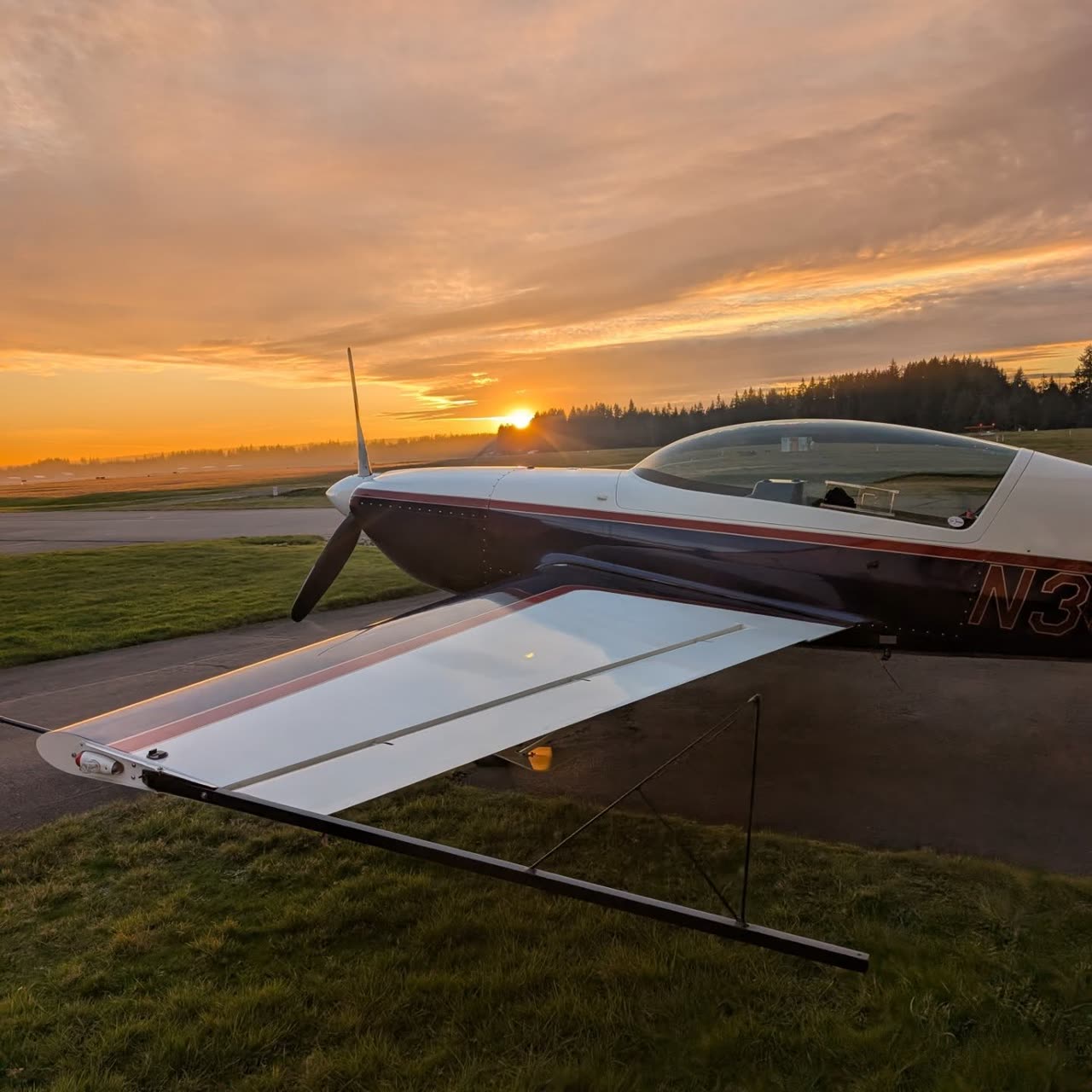 An Extra 300L parked on the ramp at sunset.